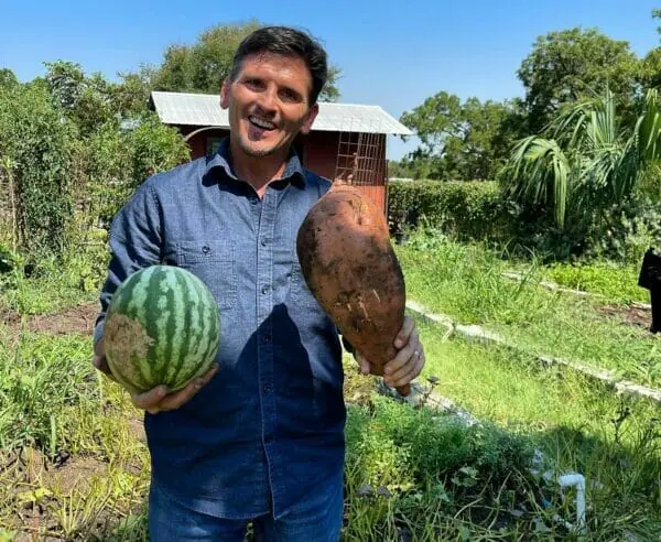 Jim Gale, founder, holding a homegrown watermelon and a large sweet potato